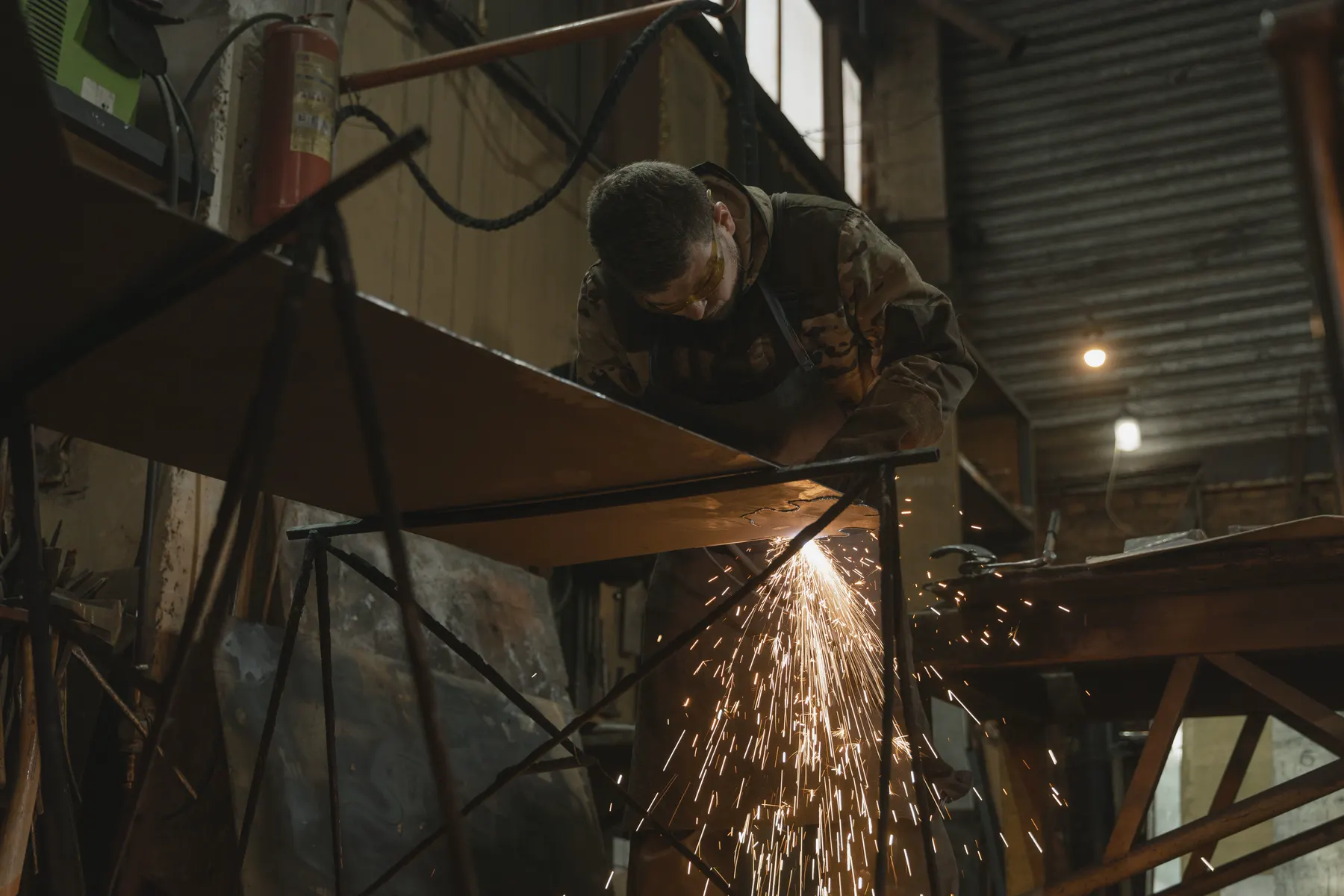 Fabricator cutting steel in a workshop with sparks flying